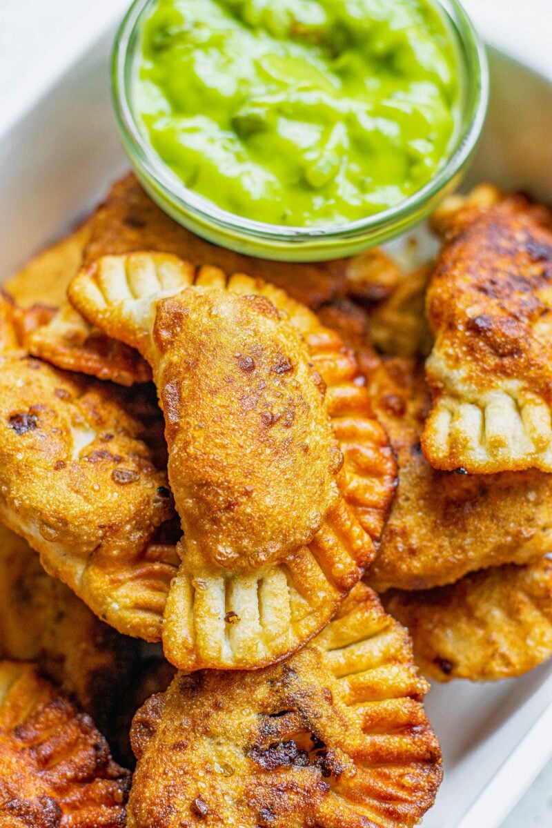 Empanadas are golden brown and fully cooked on a white plate. 