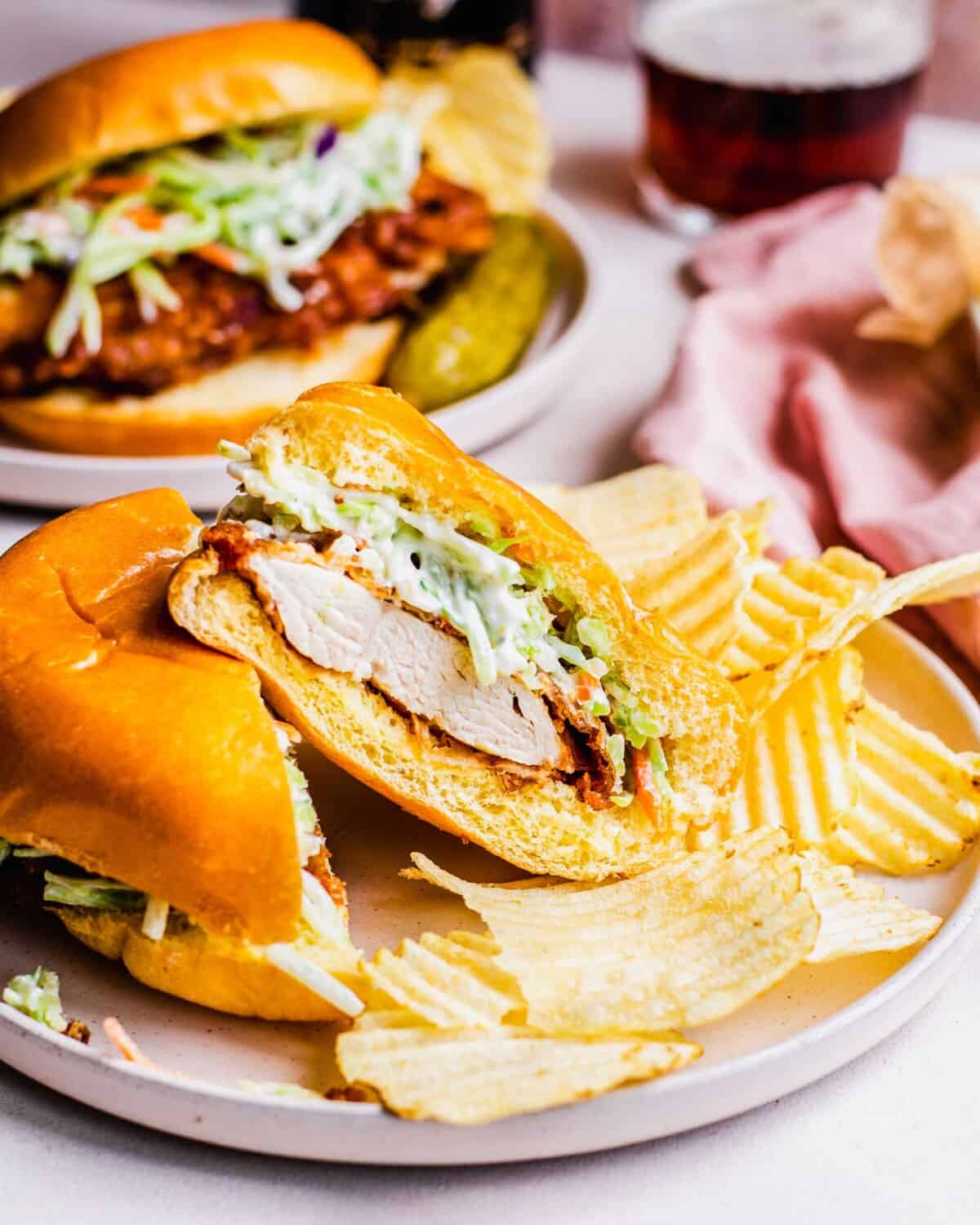 A fried chicken sandwich has been sliced in half, revealing perfectly cooked white meat.