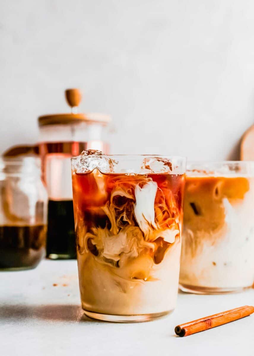Skip the line and make an Iced Brown Sugar Oatmilk Shaken Espresso at home! This easy Starbucks copycat recipe is plant-based & delicious. A small glass is filled with oat milk, ice, and espresso.