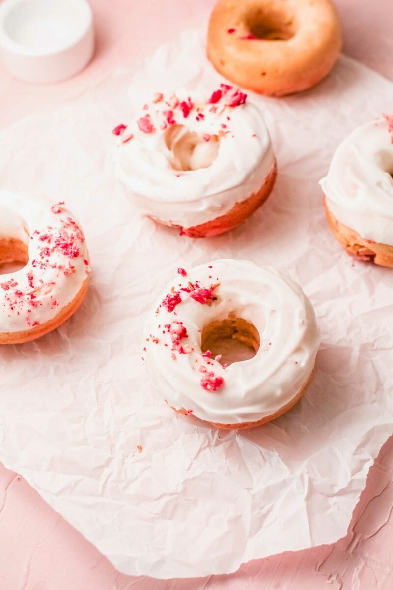 Donuts are placed on a sheet of parchment paper.