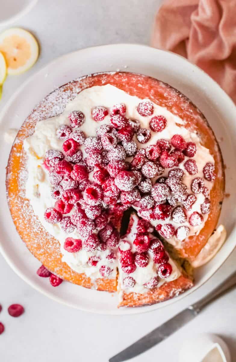 A slice has been taken out of a raspberry cake. 