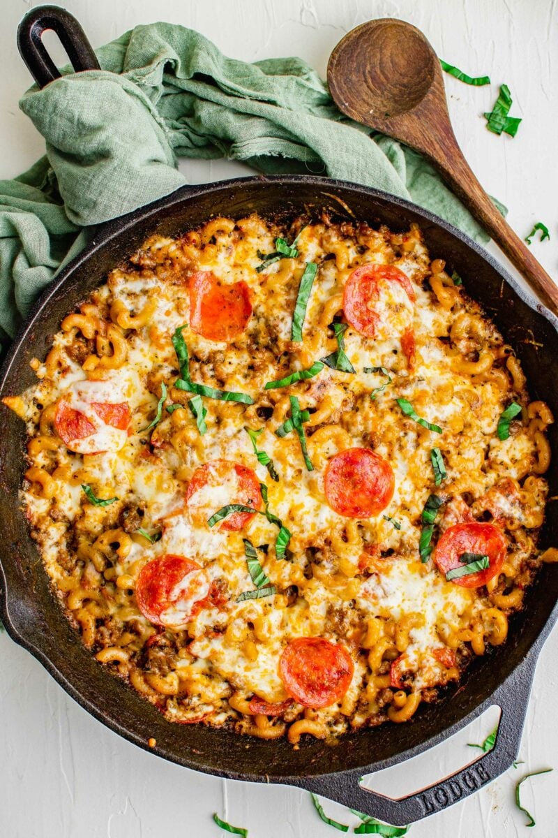 Cheesy pasta has been baked in a large black skillet. 