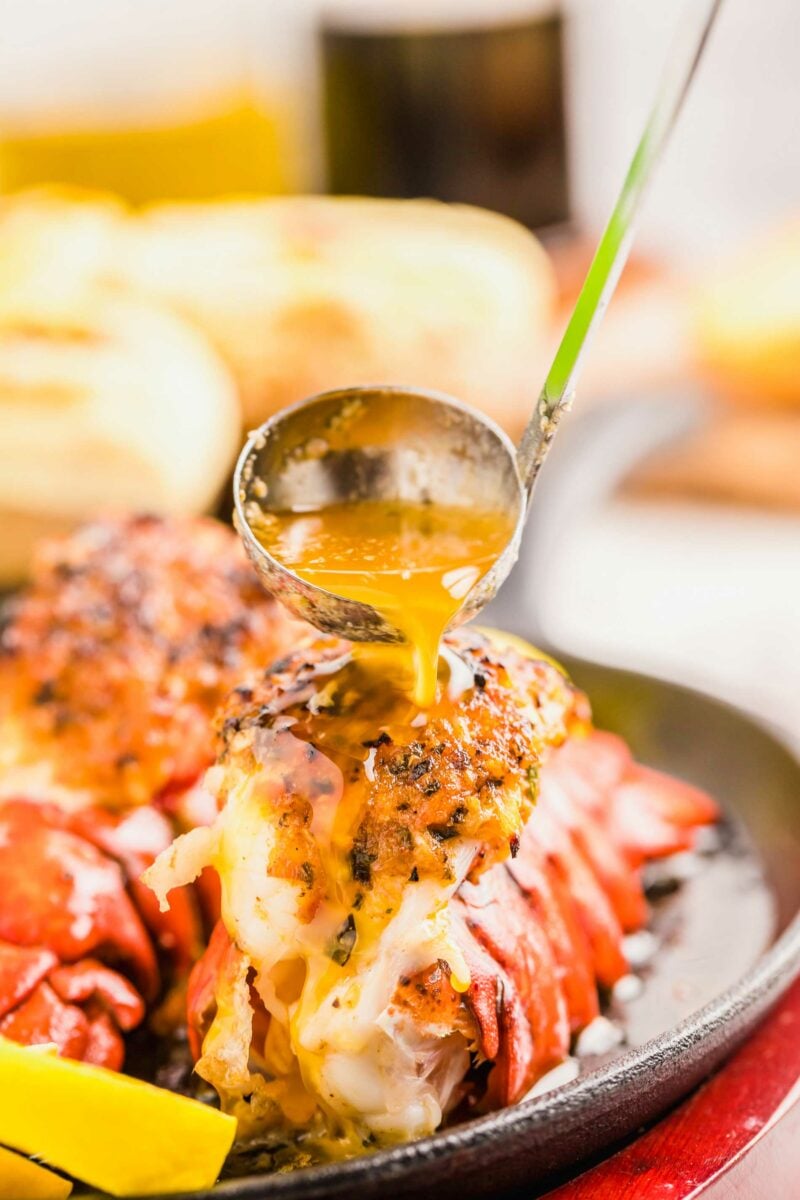 Butter is being poured atop a cooked lobster tail. 