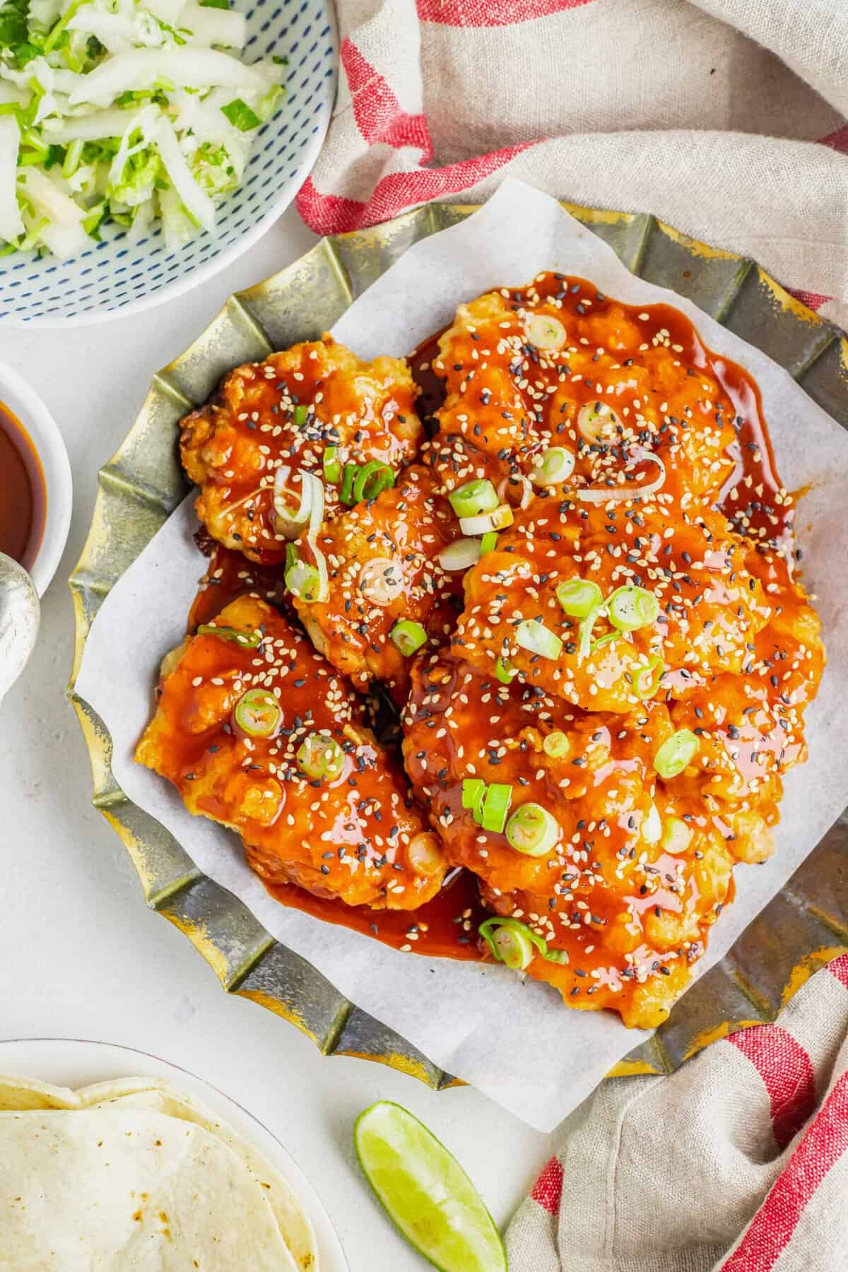 Chicken thighs are tossed in sauce and topped with scallions and sesame seeds. 