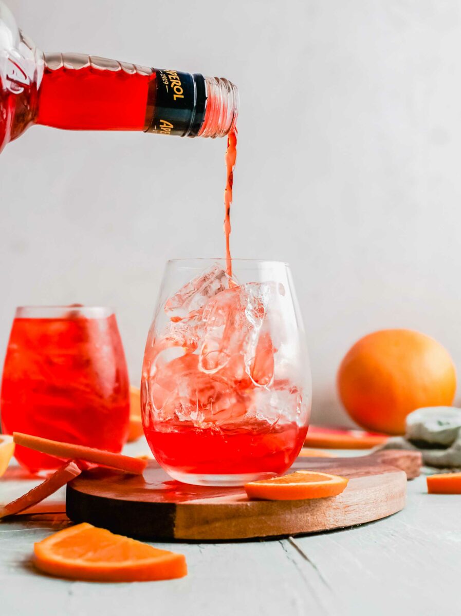 Aperol is being poured into a wine glass.