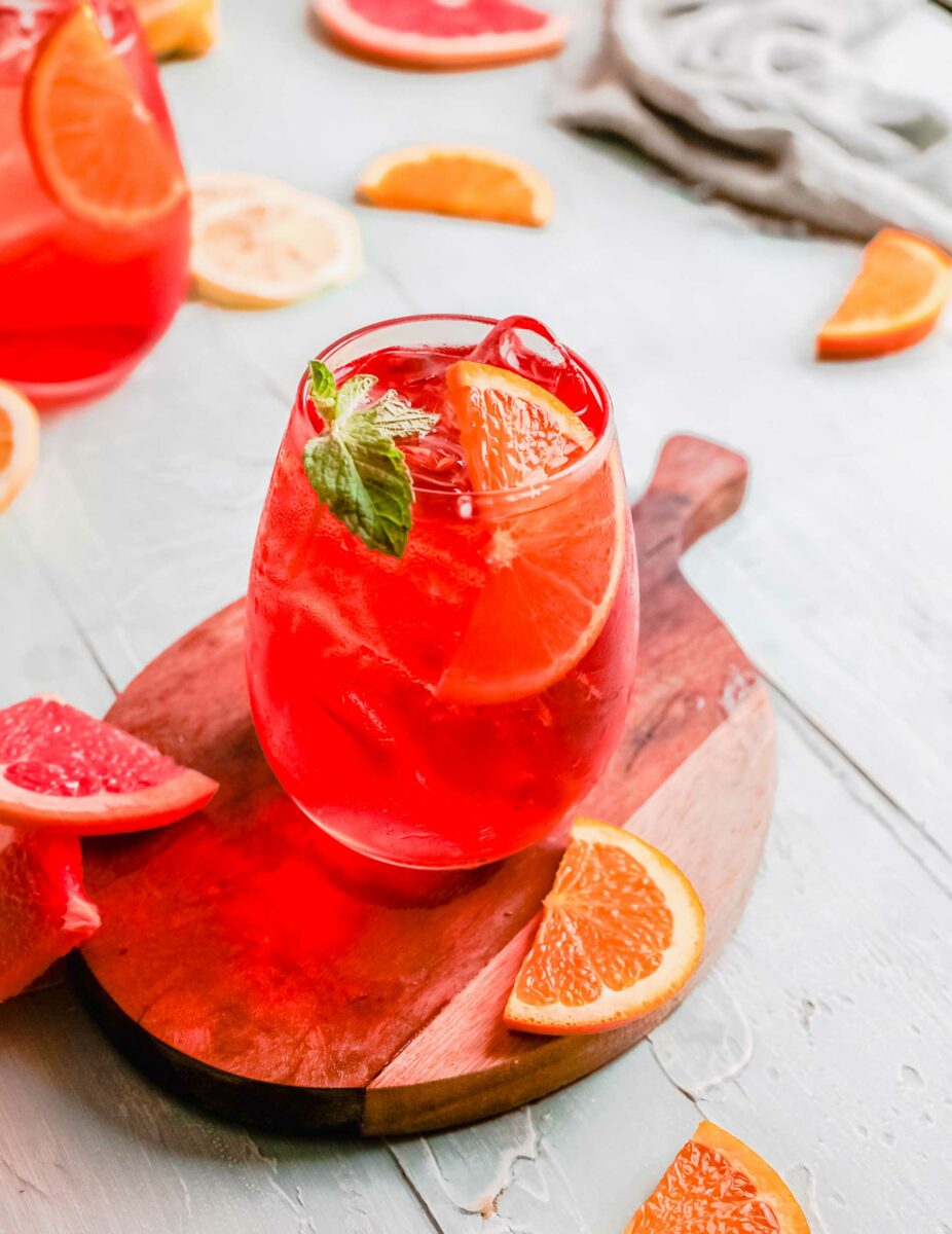 An aperol spritz is garnished with a mint leaf and an orange slice. 