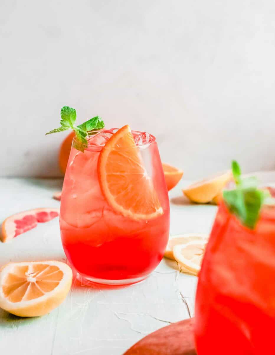 A wine glass is filled with aperol spritz, ice, and an orange slice. 