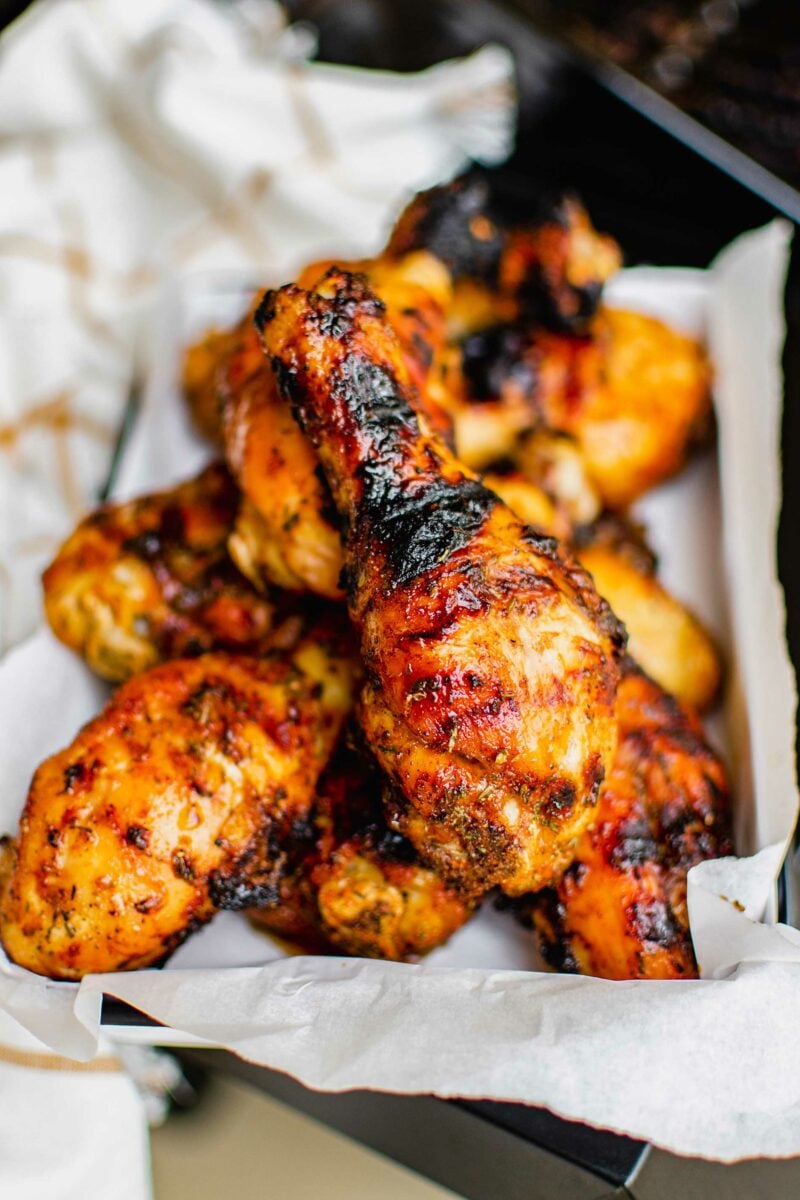 Chicken legs are finished grilling, and parts of them are blackened. 