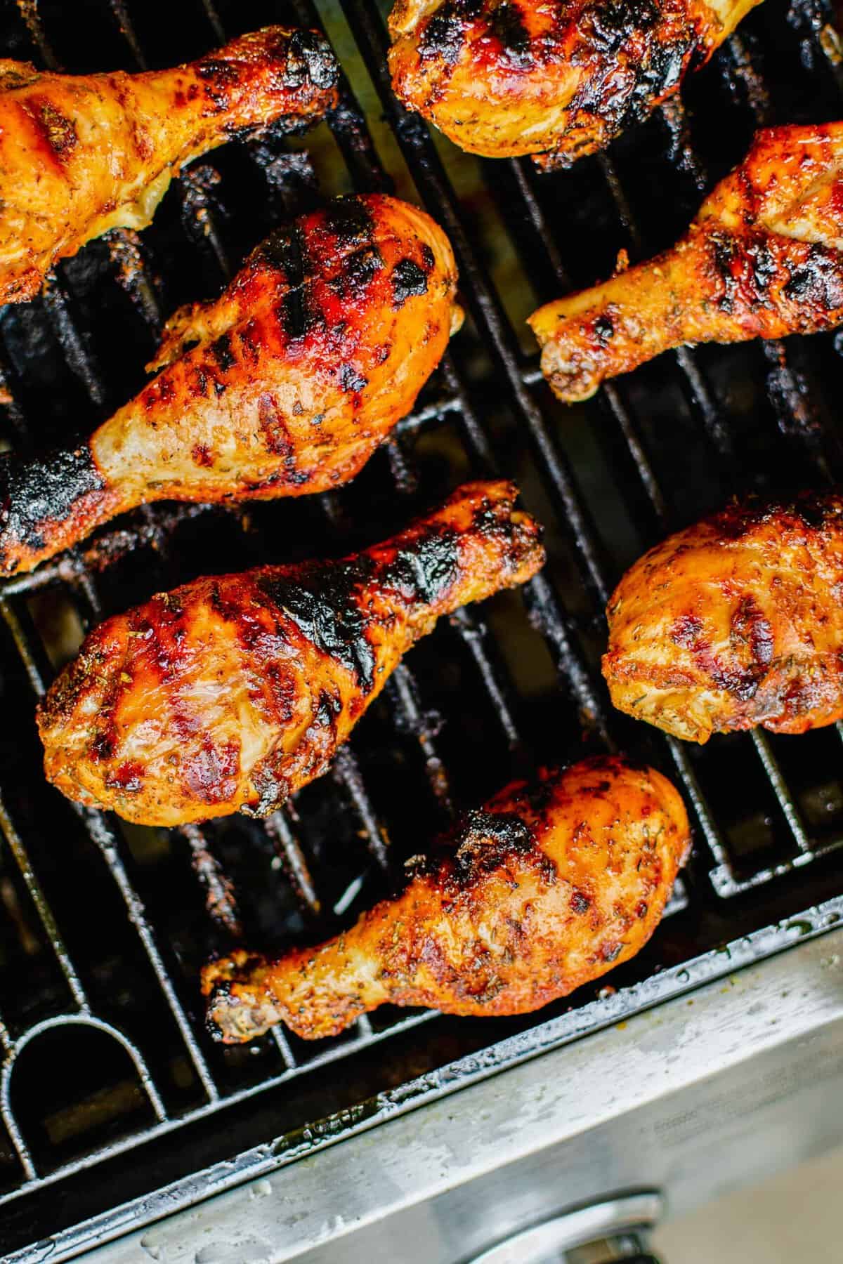 Chicken legs are cooked on a black grill. 
