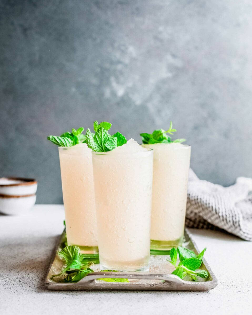 A metal tray holds several cups filled with frozen mint julep. 