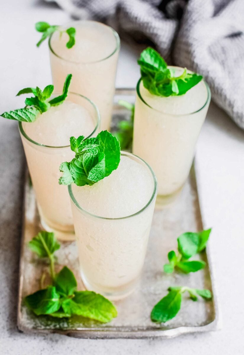 Mint sprigs are placed on and around four mint juleps. 