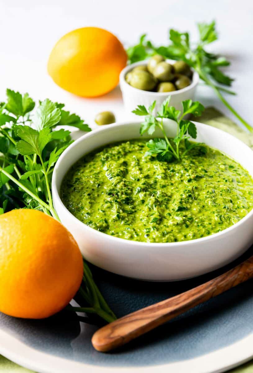 A small white bowl is filed with green gremolata. 