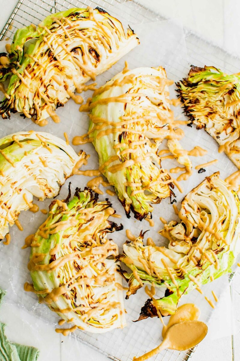 Several slices of cabbage have been grilled and are drizzled with a light orange sauce. 