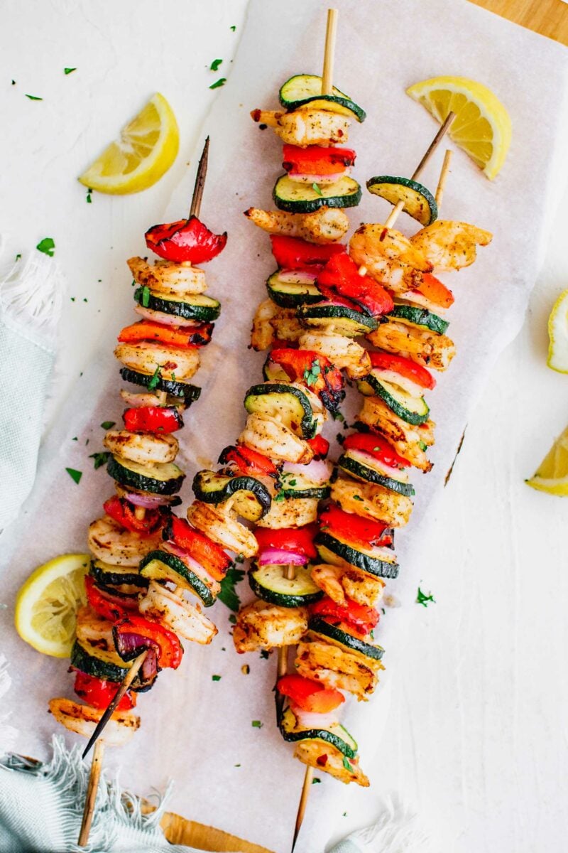 Lemon slices are placed next to the shrimp kebobs. 