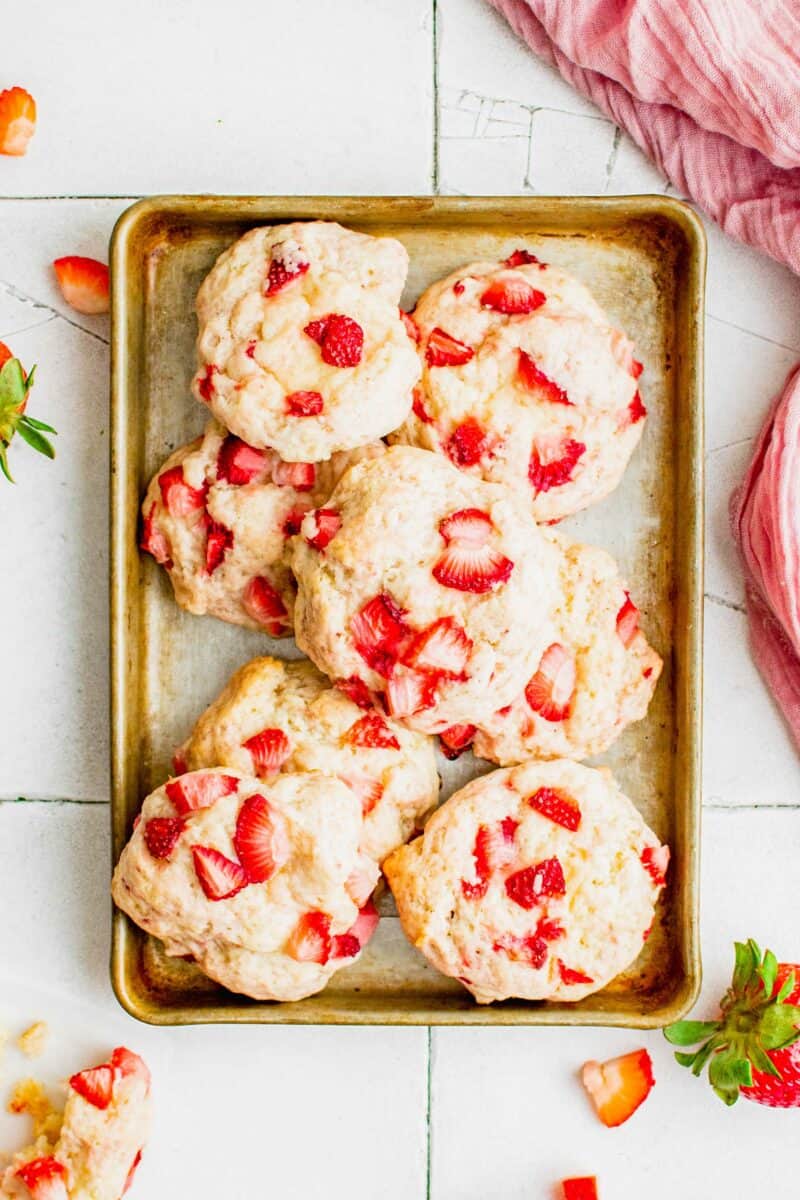 A batch of strawberry shortcake cookies are placed on a baking sheet. 