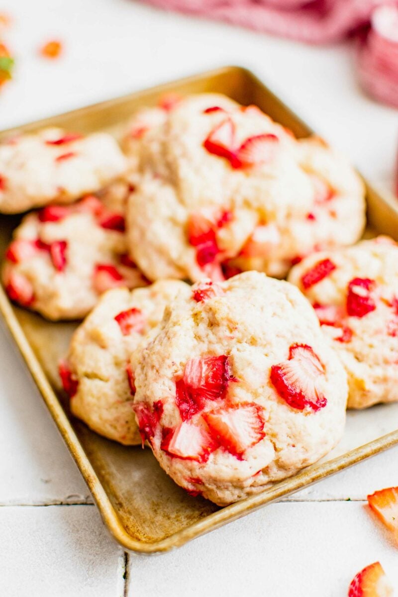 Many cookies are baked and placed on top of one another on a baking sheet. 