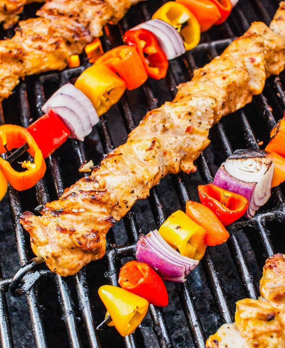 Chicken skewers and veggie skewers are on a grill. 
