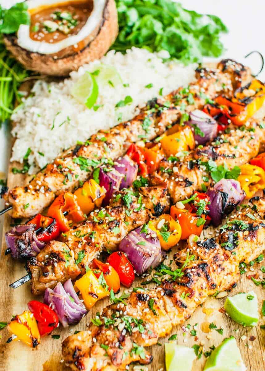 Chicken skewers are lined up with vegetable skewers. 