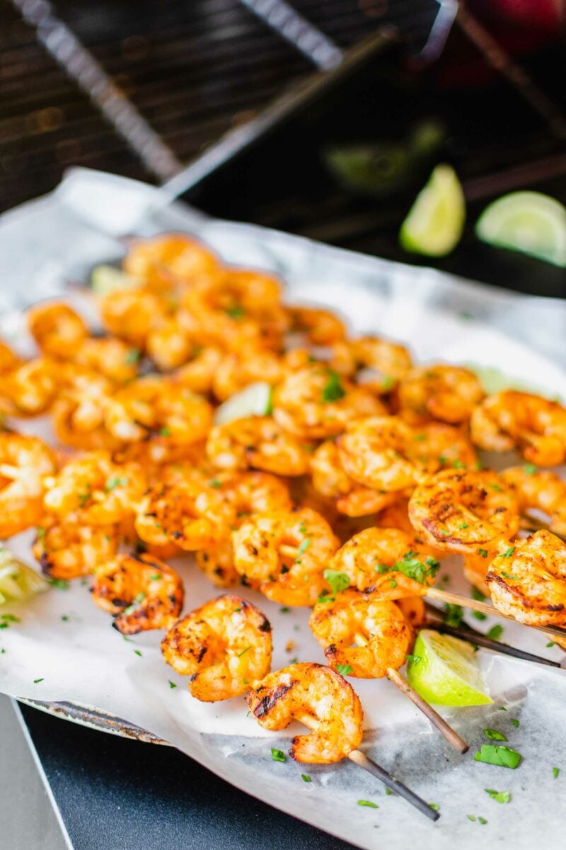 Grilled shrimp skewers are on a sheet of parchment paper. 