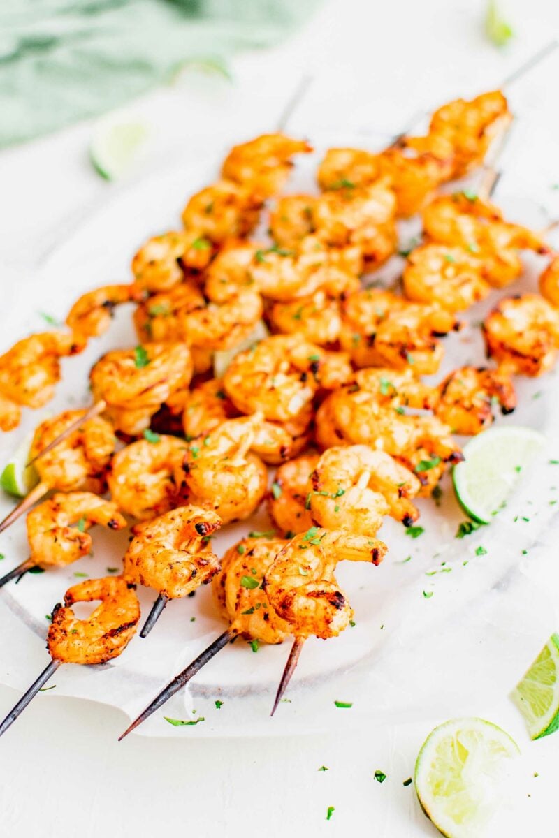 Shrimp skewers are garnished with cilantro and lime slices. 