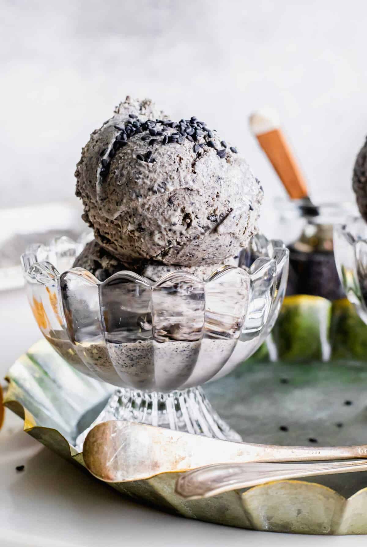 Two scoops of black sesame ice cream are in a small glass bowl.