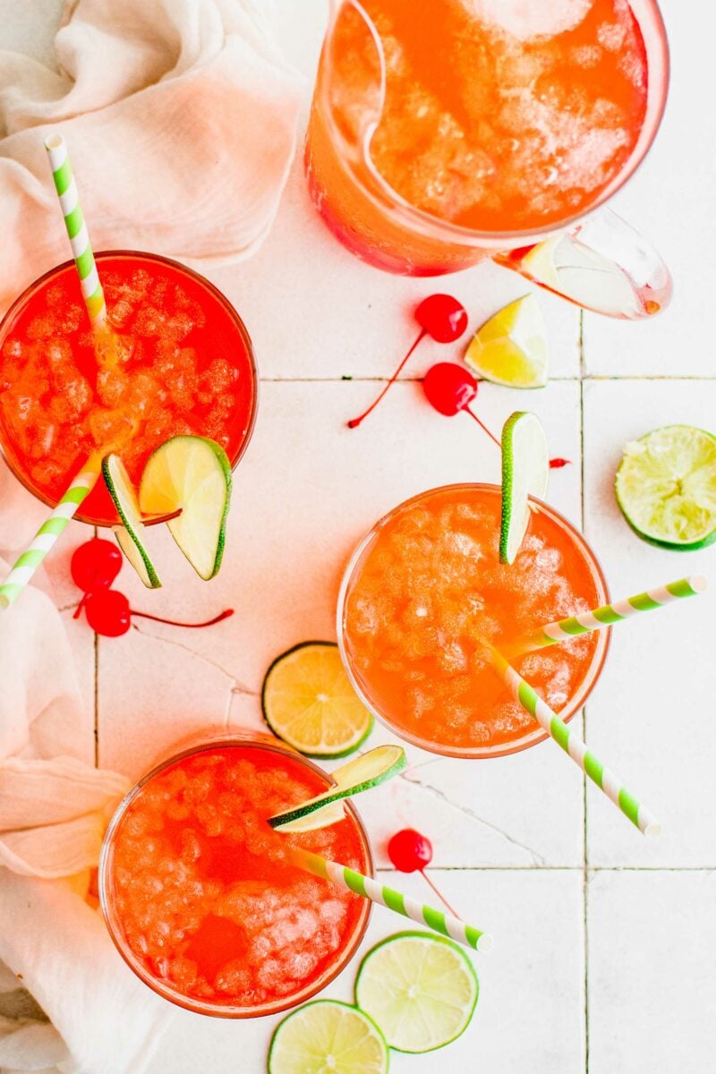 Four cherry limeades are placed on a white surface. 