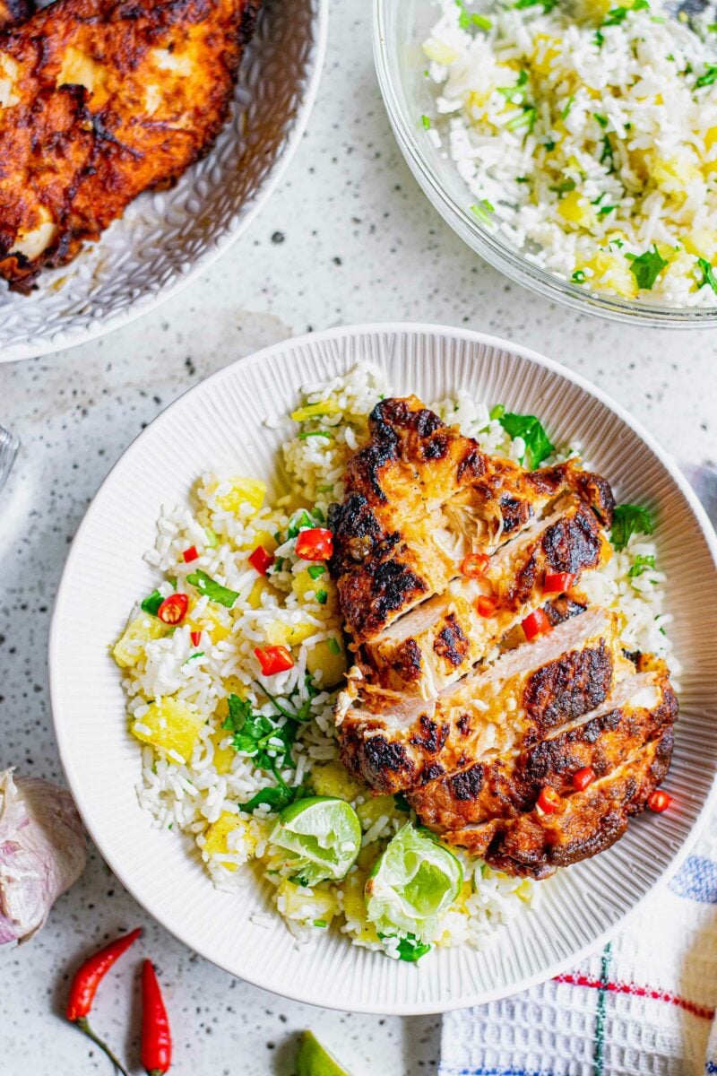 Sliced chicken breast is placed on top of pineapple fried rice. 