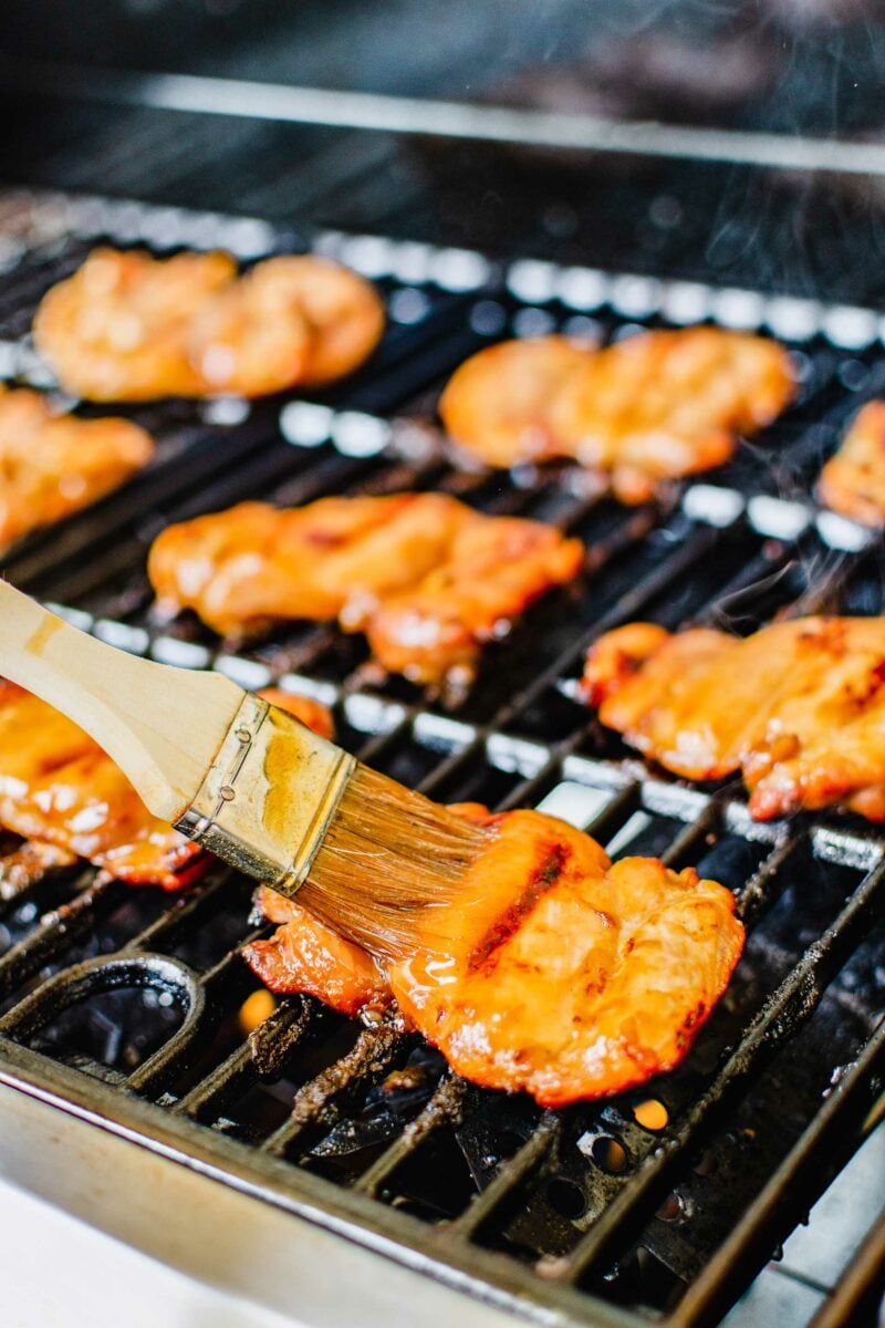 Glaze is being brushed on a chicken thigh. 