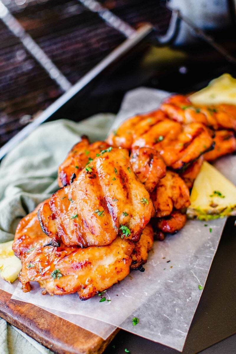 Grilled chicken thighs are placed on a sheet of parchment paper. 