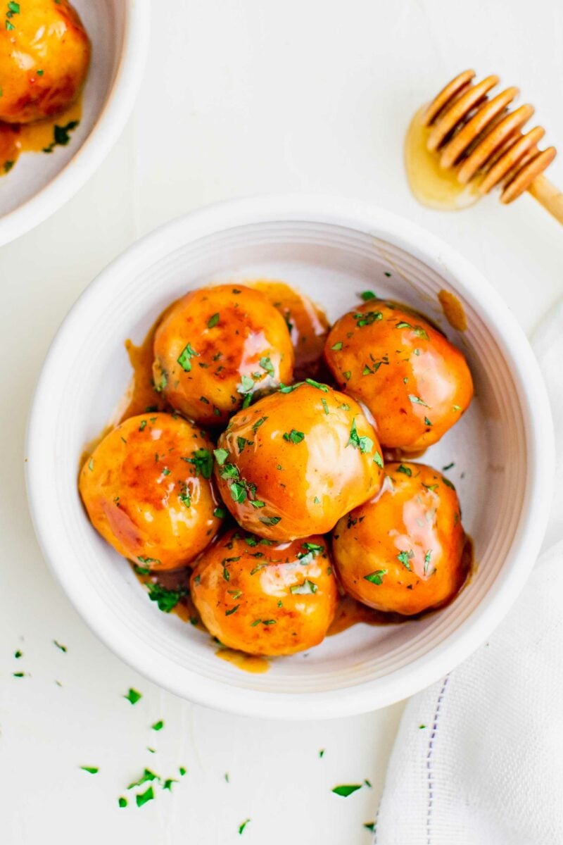 A white bowl contains a serving of chicken meatballs. 