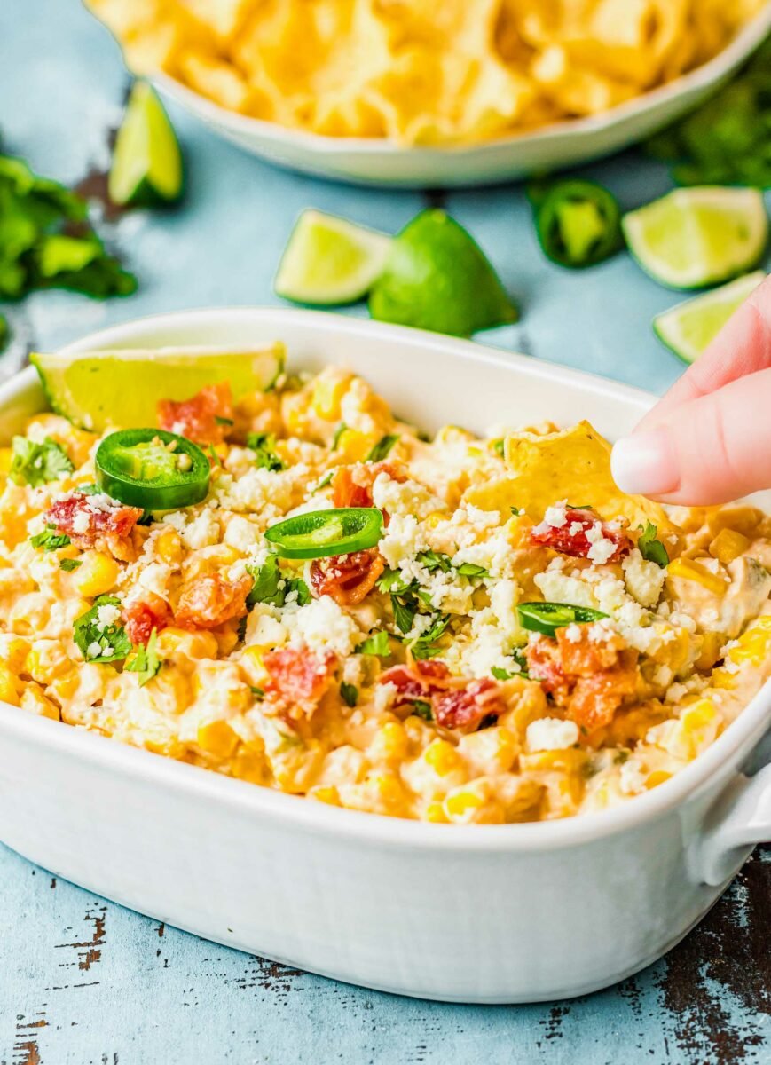 A chip is being dipped into jalapeño corn dip. 