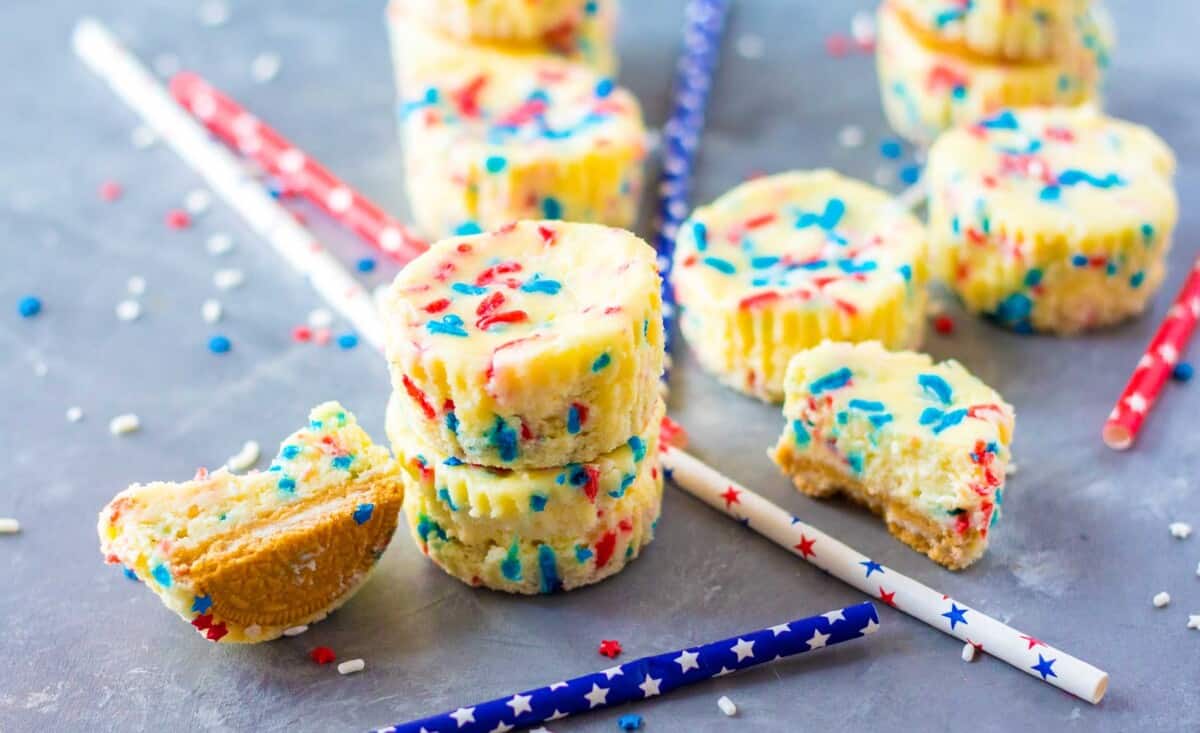 Star spangled straws are placed all around mini cheesecakes. 