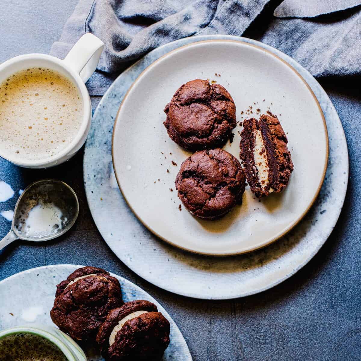 A mug filled with coffee is placed next to a plate with three mocha sandwiches. 