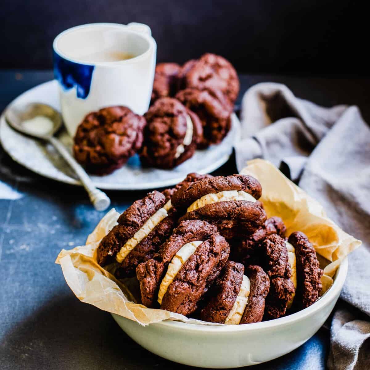 A bowl filled with ice cream sandwiches is placed next to a plate with more. 