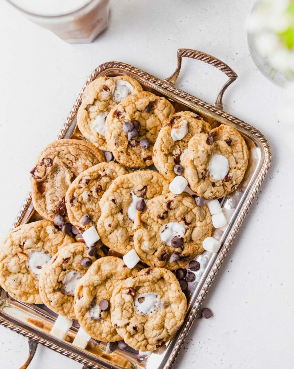 Marshmallows and chocolate chips are spread out over a tray of cookies. 