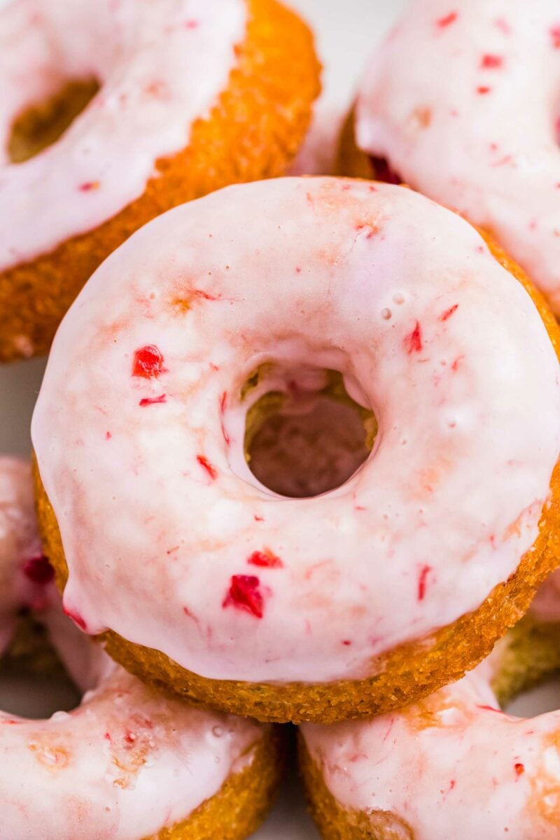 A baked buttermilk donut has been glazed with pink homemade frosting. 