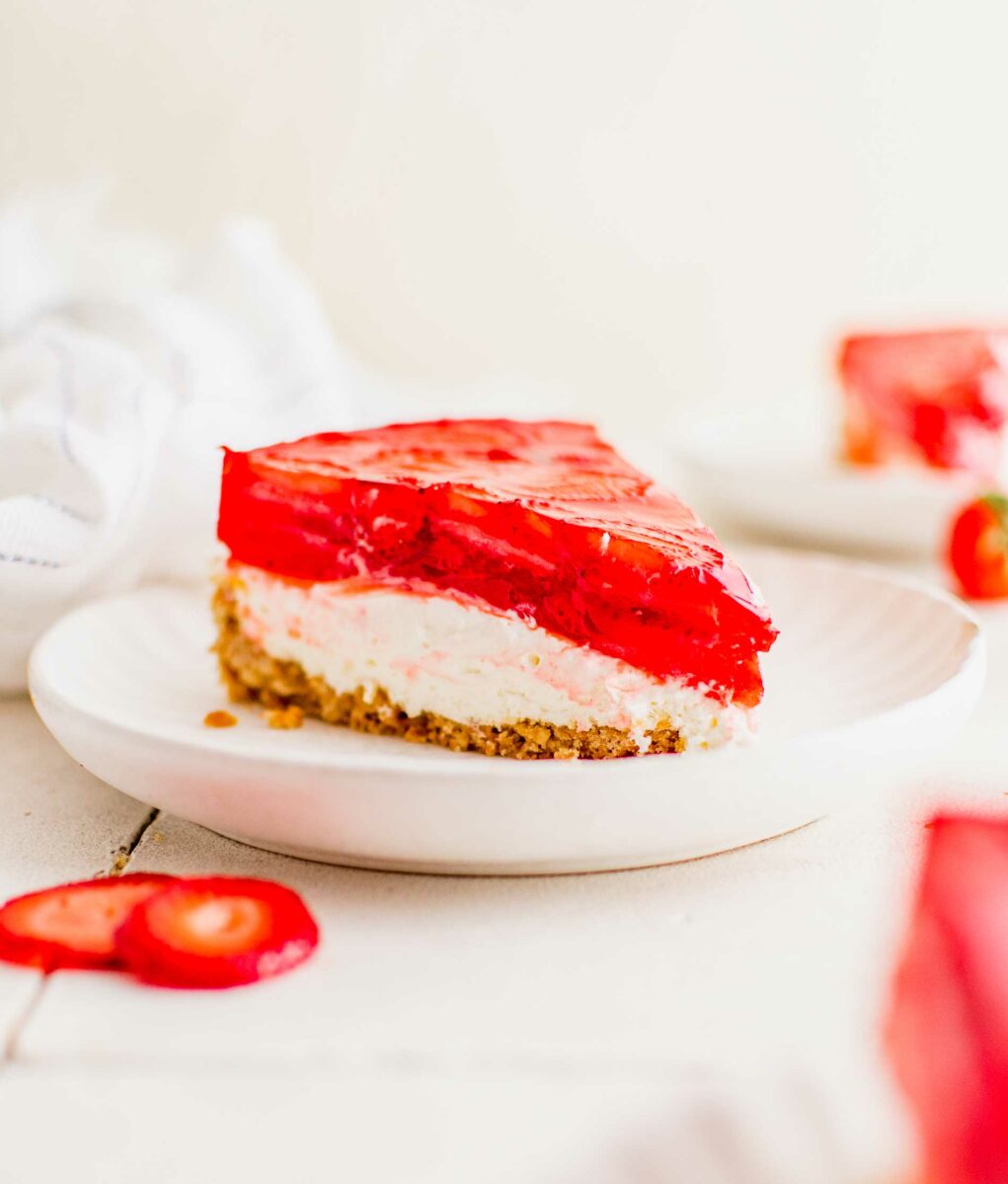 A slice of strawberry pretzel pie is presented on a white plate. 