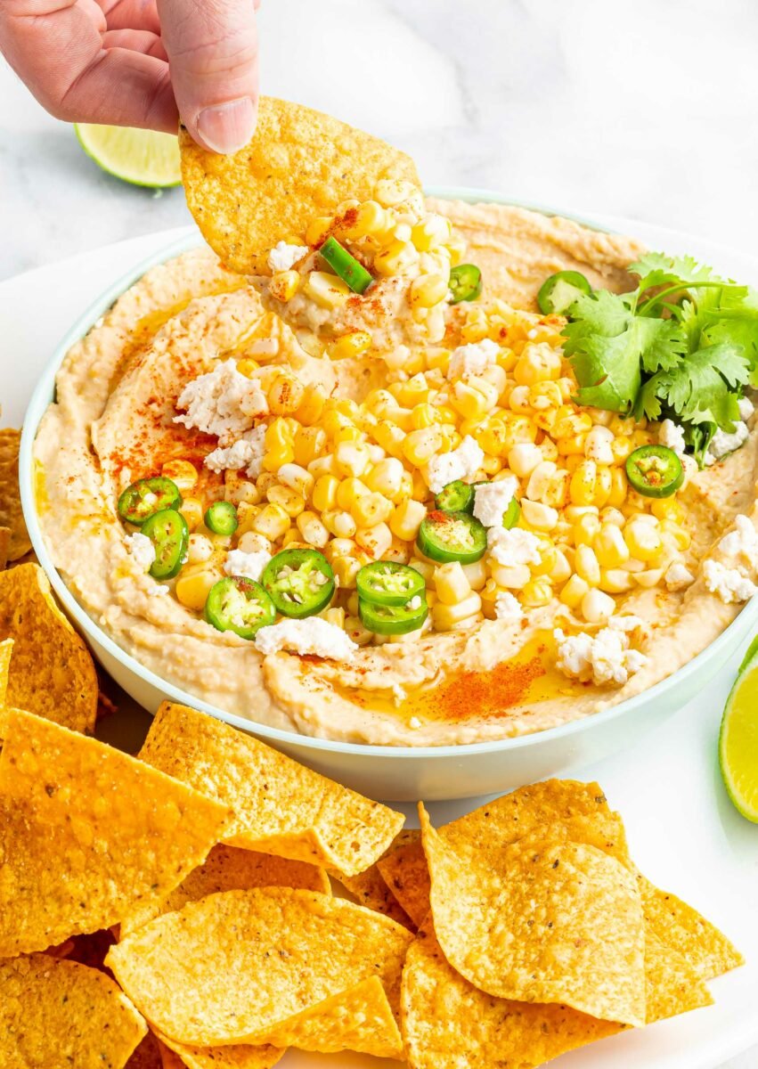 A chip has been dipped into street corn hummus. 