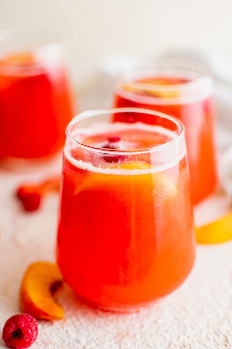 Several glasses of summer punch are on a white surface.