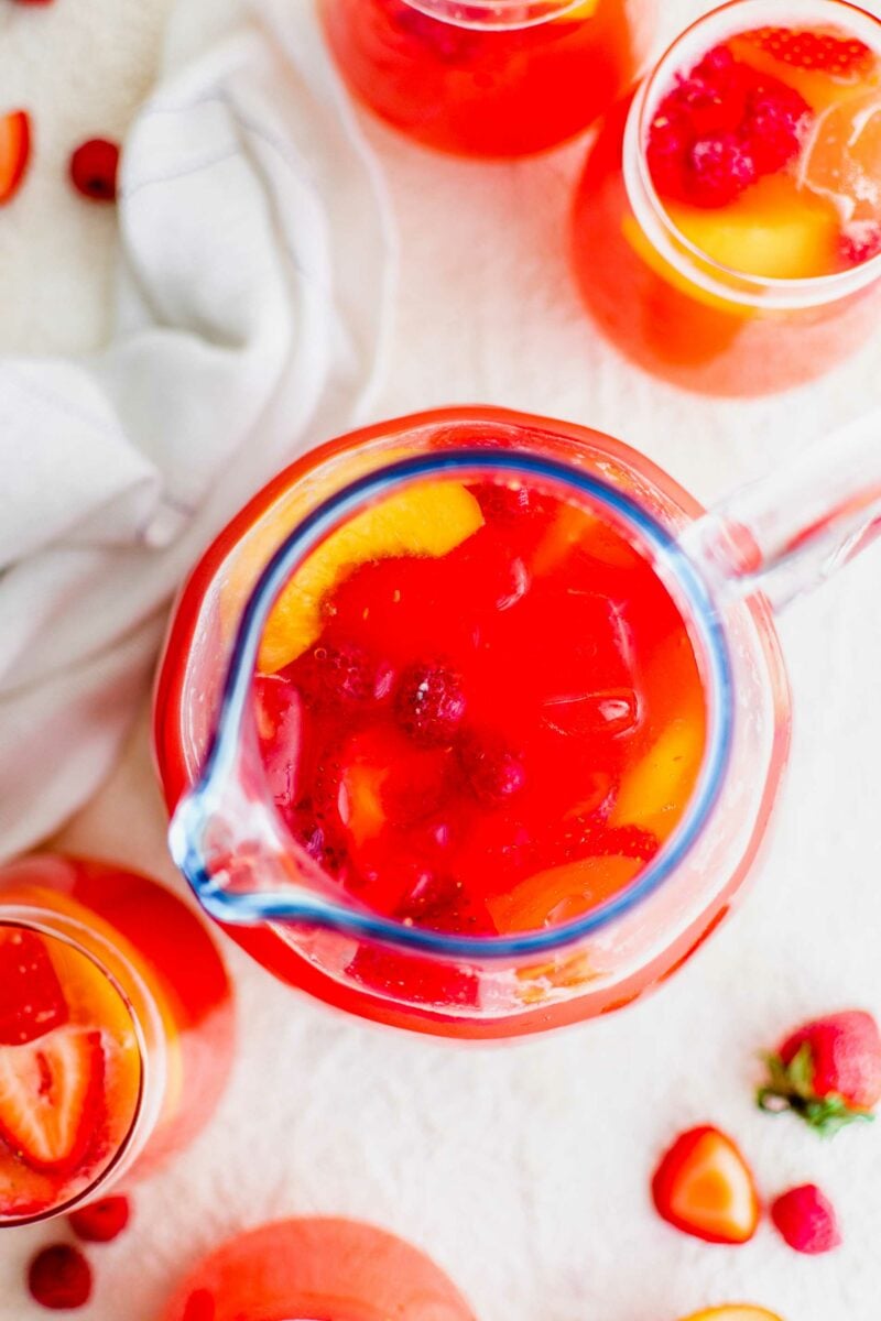 A pitcher of summer punch is placed on a white surface. 