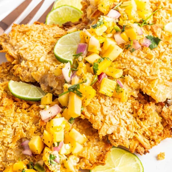 Baked tortilla crusted tilapia is garnished with limes and mango.