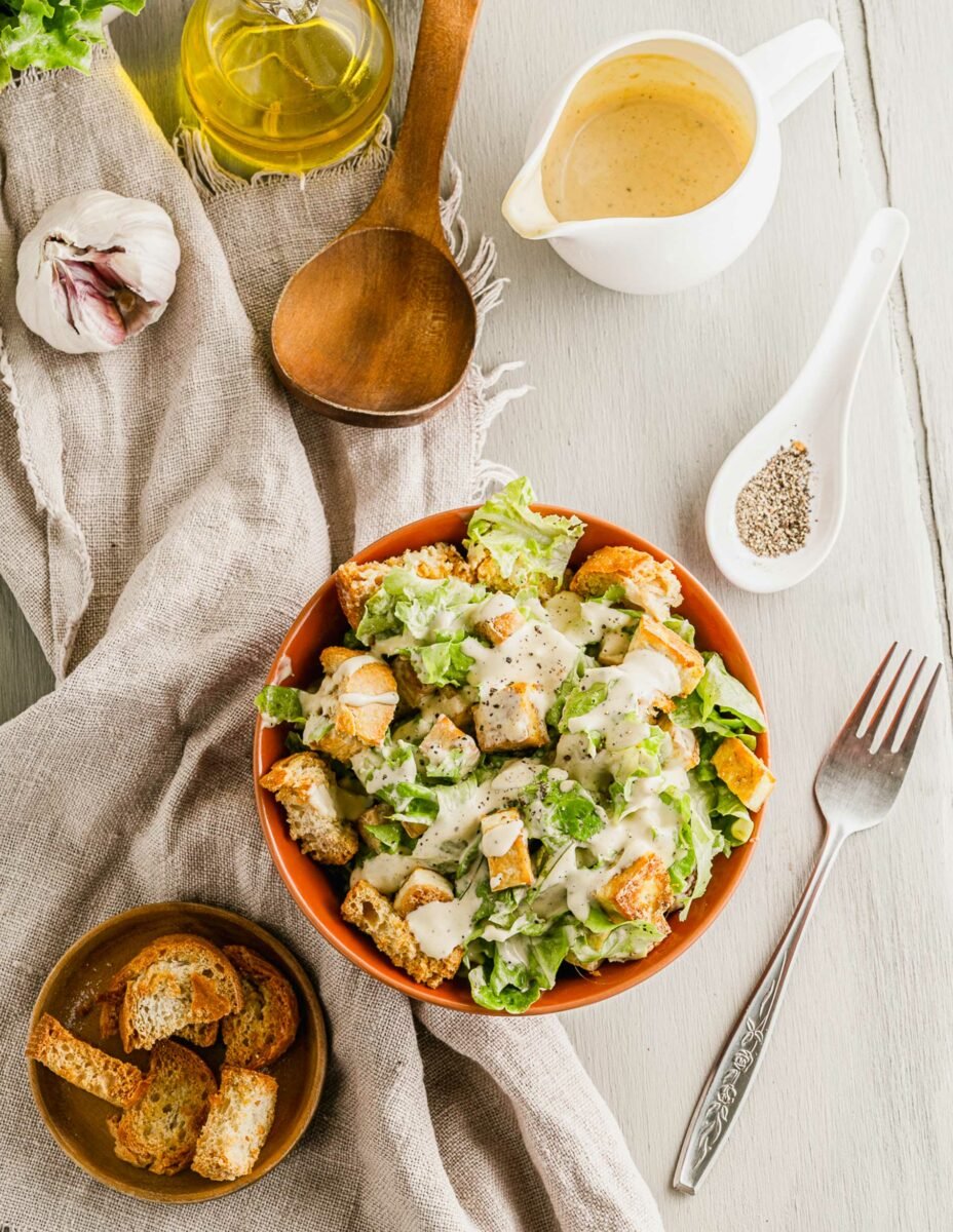 A fork is placed next to a bowl filled with Caesar salad. 