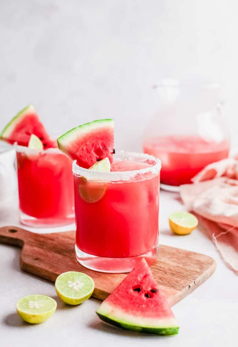 Several watermelon palomas are on a white countertop. 