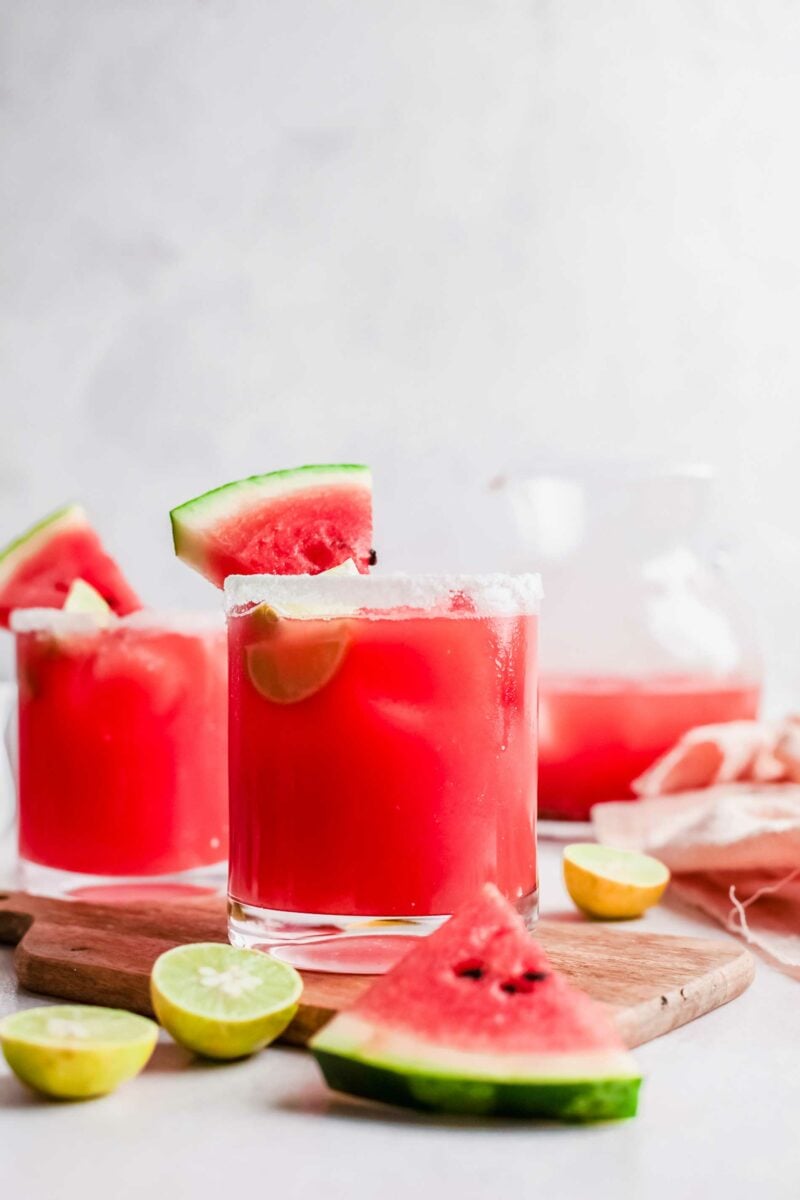 Vibrant pink watermelon Palomas are placed on a wooden surface. 