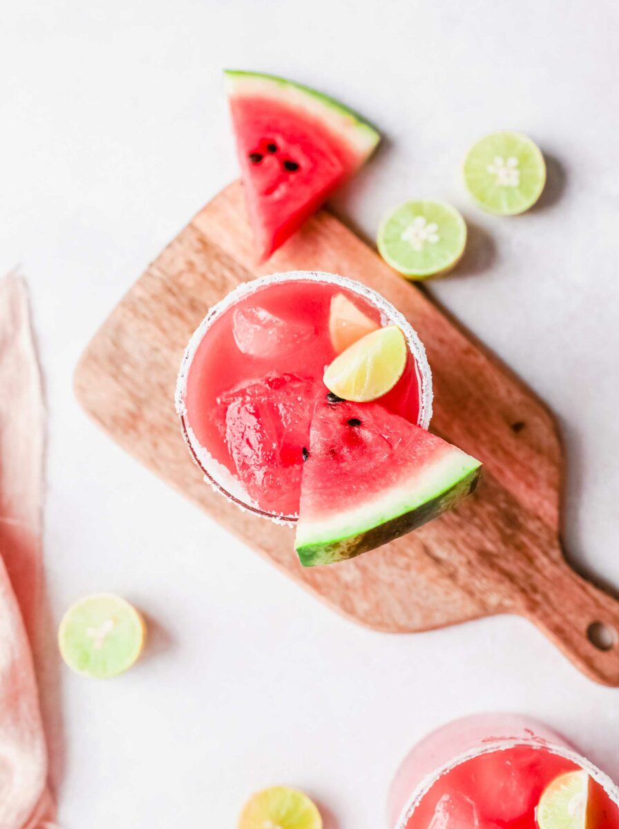 A juicy slice of watermelon is placed in a glass of paloma. 