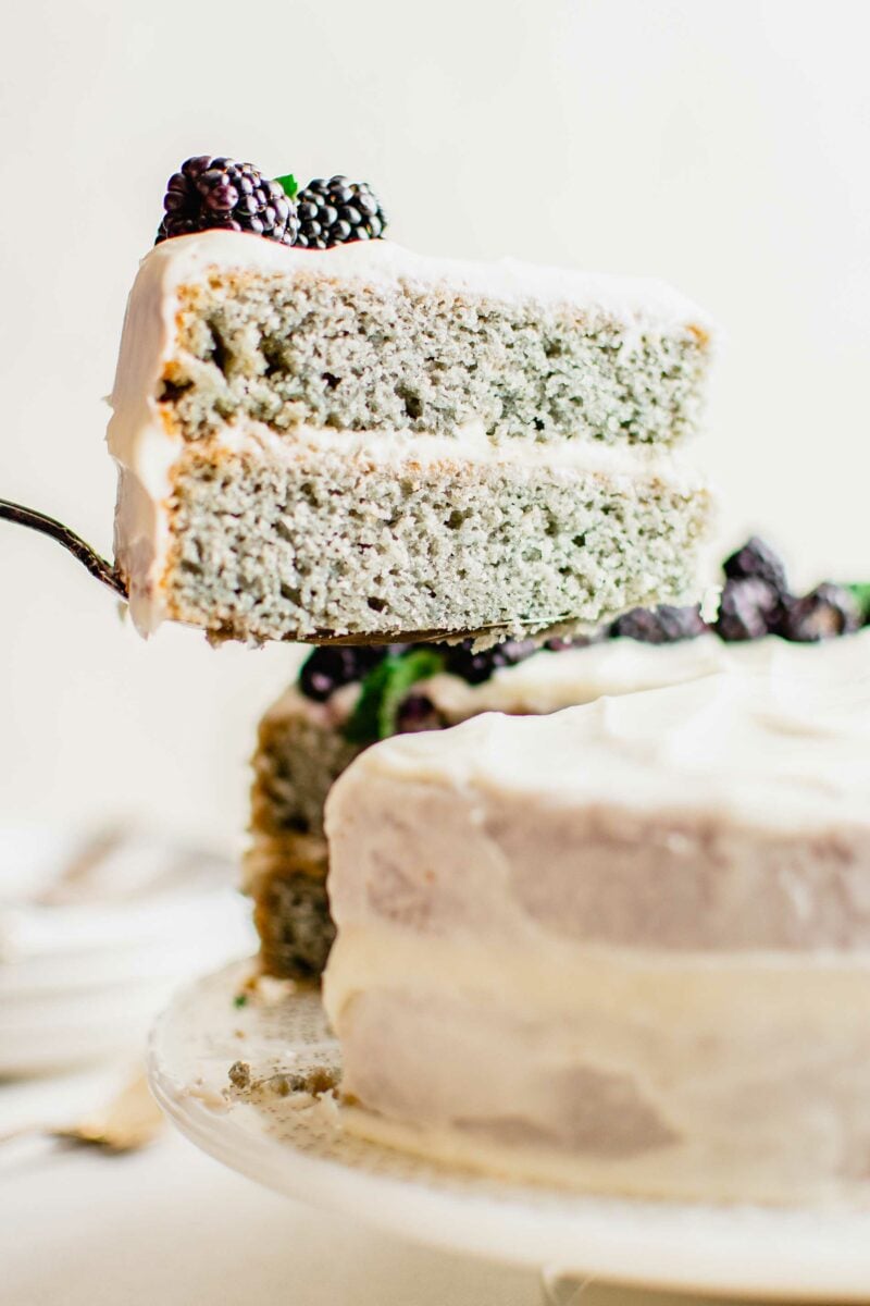 A slice of blackberry cake is being removed from the rest of the cake. 