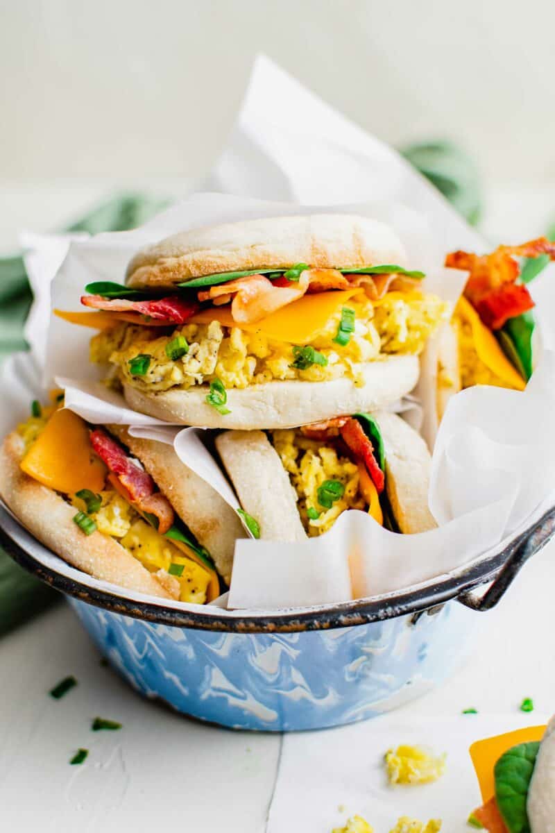 Several sandwiches are placed with parchment paper in a bowl. 