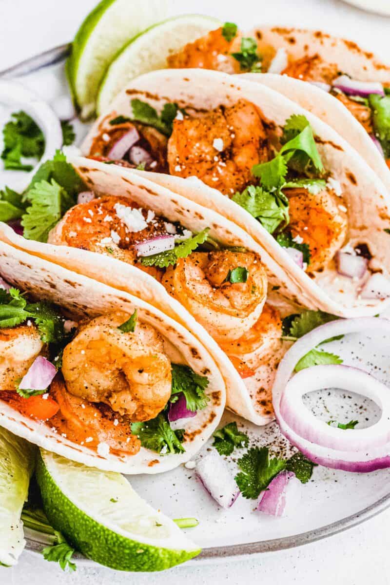 Several shrimp tacos are placed on a white surface.