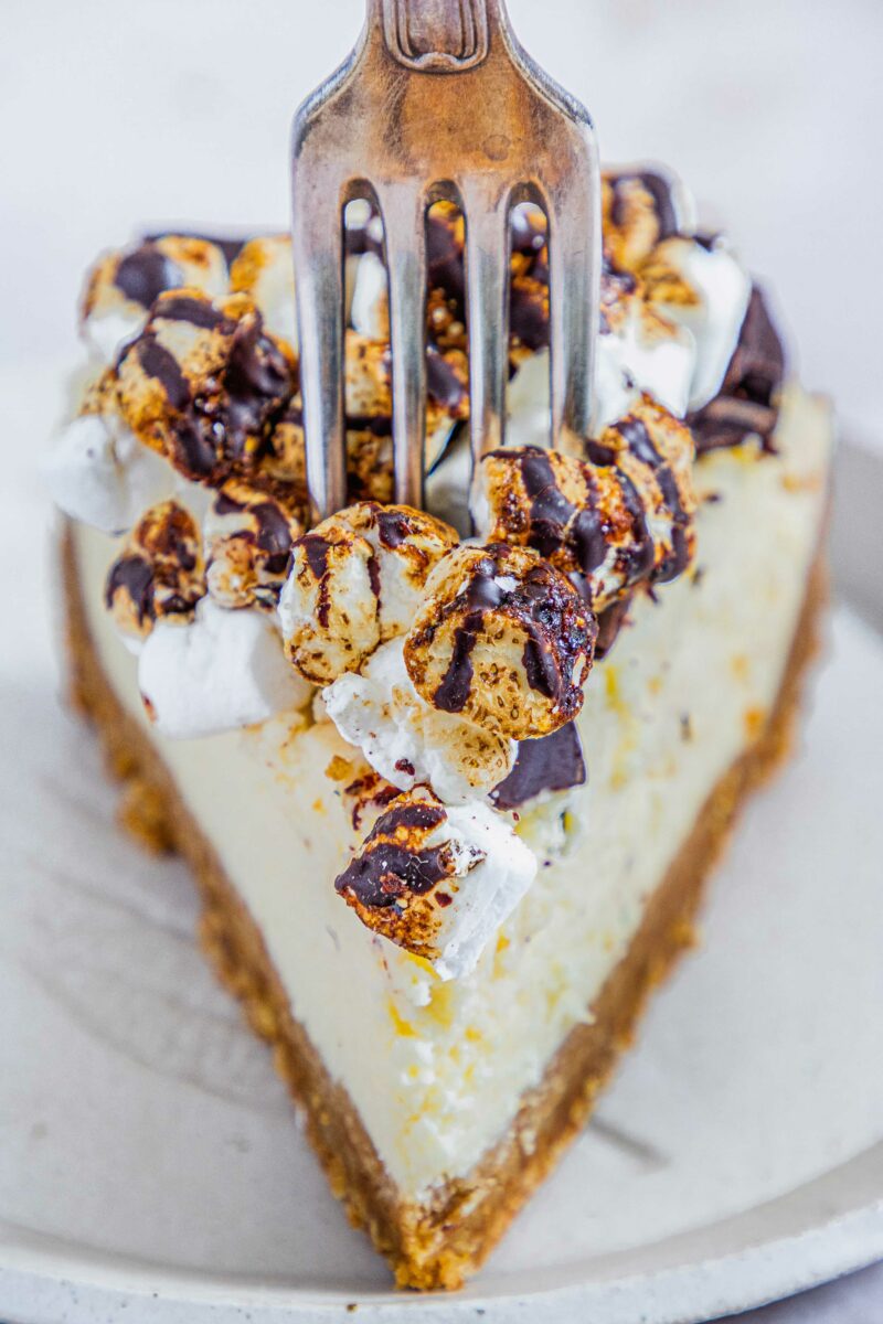 A fork is plunging into a slice of s'mores cheesecake. 