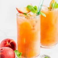 Two glasses are filled with spicy peach drinks.